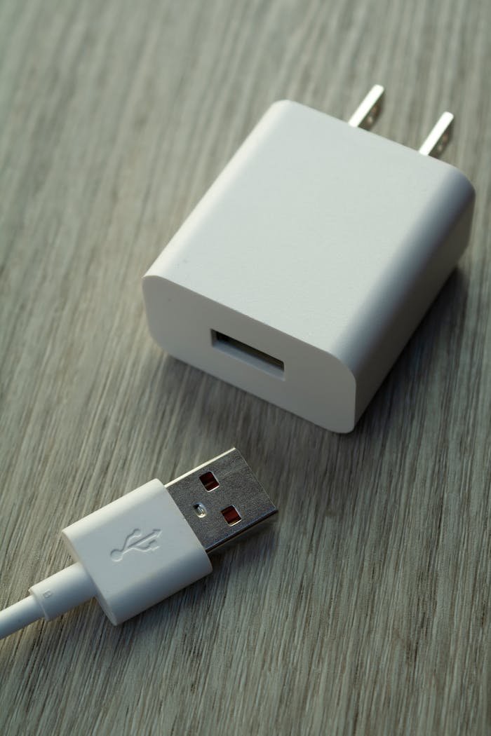 A detailed view of a white USB charger and cable on a wooden surface.