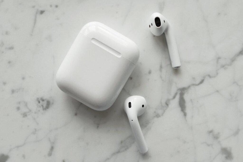 Close-up of wireless earphones and charging case on a marble surface, showcasing modern technology.