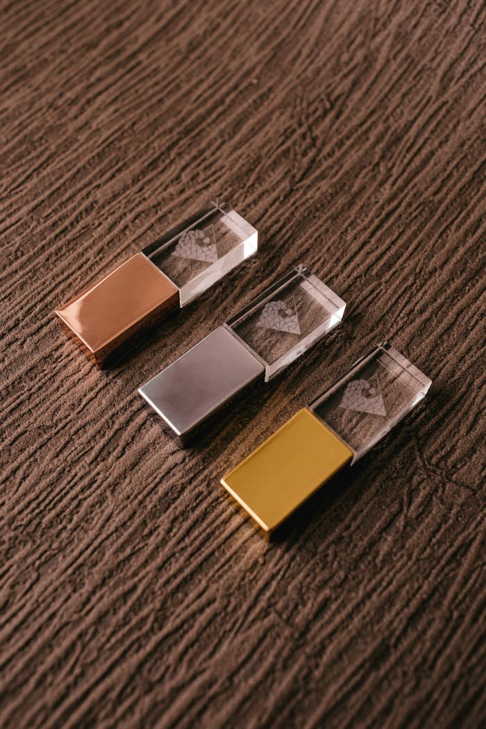 From above of set of modern memory sticks made of metal and glass materials on brown background